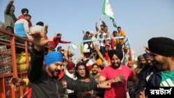 Para petani menari sambil meninggalkan lokasi demo di perbatasan Singhu, dekat Ibu Kota India, New Delhi, setelah pemerintah setuju memenuhi tuntutan mereka, termasuk berjanji akan mempertimbangkan jaminan harga untuk semua produk pertanian, Sabtu, 11 Desember 2021. (Foto: