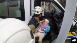 This photo provided by the Syrian Defense White Helmets shows a civil defense worker carrying a child after shelling hit a street in the town of Nairab, in the eastern province of Idlib, Syria, Apr. 7, 2019.