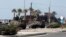Lebanese Army soldiers on armored vehicles move towards an area of clashes in Sidon, southern Lebanon, June 23, 2013. 