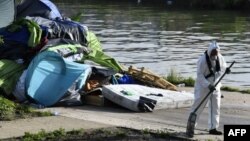 Un ouvrier nettoie le camp de fortune des migrants du Millénaire le long du canal de Saint-Denis près de la porte de la Villette, au nord de Paris, suite à son évacuation le 30 mai 2018.