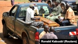 Une famille ougandaise est assise à côté du cercueil d'un parent décédé dans une camionnette à l'hôpital Mulago, à Kampala le 13 juillet 2010.