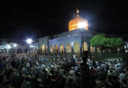 FILE - Syrian Shiites pray outside the shrine of Sayyidah Zaynab in Damascus, June 28, 2016.