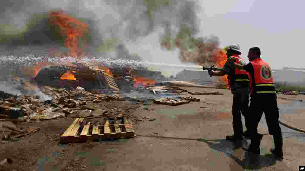 Palestinian firefighters try to extinguish a cargo terminal at Karni Crossing between Israel and Gaza after it was shelled by Israeli tanks, according to terminal's employees, July 12, 2014. 