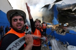 A Palestinian firefighter reacts as he works to put out a fire at a sponge factory after it was hit by Israeli artillery shells, according to witnesses, in the northern Gaza Strip, May 17, 2021.