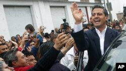 Enrique Pena Nieto (kanan), yang diperkirakan akan memenangkan pilpres Meksiko, melambai kepada para pendukungnya, Minggu (1/7).