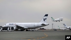 FILE - In this Feb. 7, 2016, photo, an Iranian Mahan Air passenger plane takes off as a plane of Iran's national air carrier Iran Air, left, is parked at Mehrabad airport in Tehran, Iran.