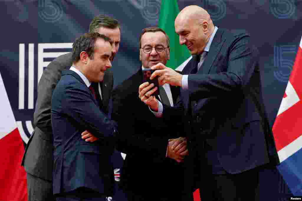 Defense ministers from France, Poland, Germany and Italy look at a mobile phone as they arrive for a meeting to discuss action in support of Ukraine, at the Val de Grace former military hospital in Paris.