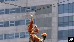 Rescuers carry people acting as victims as they rappel down a high-rise building during the National Earthquake Drill at the Ortigas commercial center as part of a disaster preparedness effort in suburban Pasig City, east of Manila, Philippines, June 2010