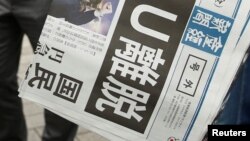 FILE - A special issue of Japan's Sankei Shimbun is handed out outside a train station in Tokyo, June 24, 2016. 