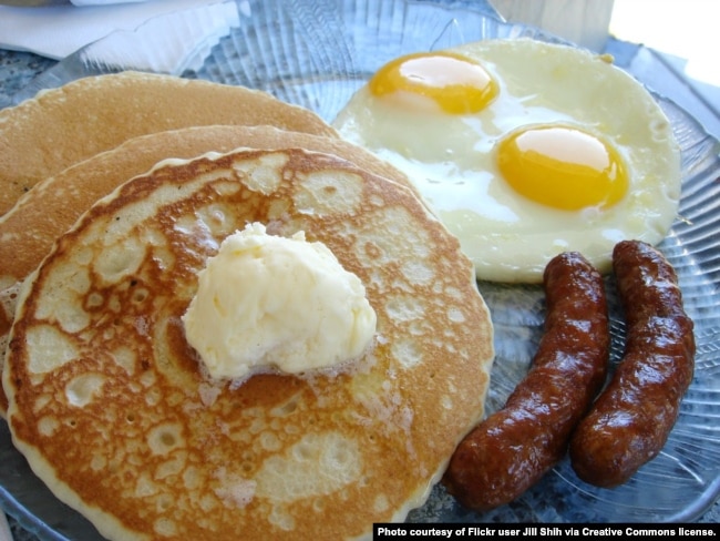 A breakfast of pancakes, eggs, and sausage.