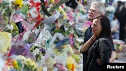 Ian Rigby (R), the stepfather of murdered British soldier Lee Rigby, and Sarah McClure look at floral tributes left at the scene of his killing in Woolwich, May 26, 2013.