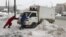 Men push a vehicle after a heavy snowfall in Moscow, Russia, Feb. 5, 2018. 