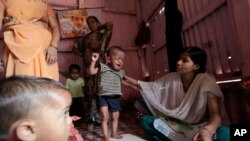 A volunteer weighs a malnourished child in Mumbai, India. A new study indicates in the same way that lack of food can harm children, violence, deprivation and neglect are also damaging their brain circuitry. (AP Photo/Rajanish Kakade)