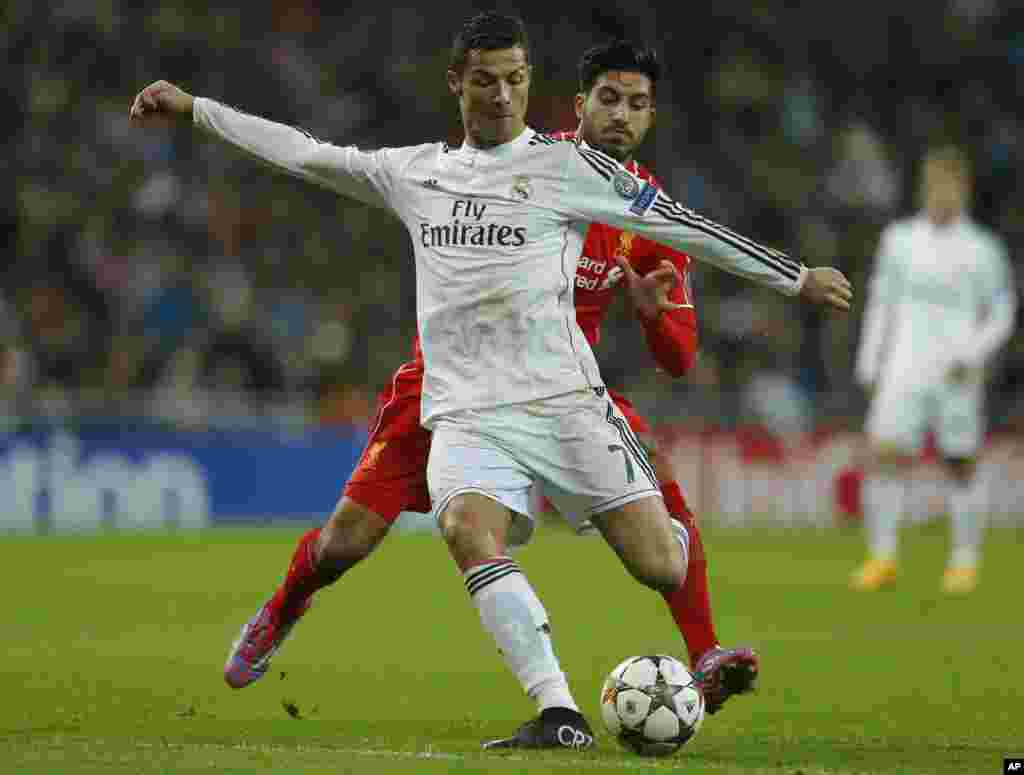 Cristiano Ronaldo du Real Madrid, devant, se lance avec le ballon dans une avec Emre Can de Liverpool lors d&#39;un match de football, Groupe B, de la Ligue des Champions entre le Real Madrid et Liverpool au stade Santiago Bernabeu à Madrid, Espagne, le mardi 4 novembre 2014.