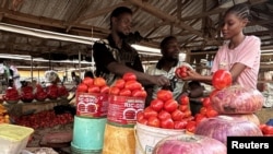 Farouk Dalhatu, um vendedor de tomates, atende um comprador num mercado comunitário de Agodo, em Lagos. FOTO DE ARQUIVO