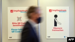 A person walks past pictograms in the vaccination center at the football stadium in Duesseldorf, western Germany, Dec. 1, 2020. Preparations are under way to install a vaccine facility amid the novel coronavirus pandemic. 