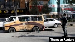 아프간 경찰이 21일 카불 시내에서 로켓 공격으로 파손된 차량의 사진을 찍고 있다.