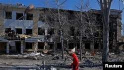 러시아 통제 지역인 우크라이나 도네츠크에서 한 여성이 포격으로 파손된 어린이 병원 건물 옆을 지나가고 있다. 러시아 당국은 이를 우크라이나 군의 공격이라고 주장했으며, 해당 병원은 당시 유지 보수 중으로 내부 환자는 없었다. 