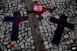 FILE - Crosses representing lost black lives are placed next to stickers that read in Portuguese "Bolsonaro Out," during a demonstration marking the day slavery was abolished in Brazil, and against government policies they say perpetuate racism and inequality, May 13, 2021