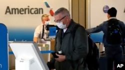 FILE - Travelers check in at the American Airline ticket counter at Greater Pittsburgh International Airport, May 7, 2020.