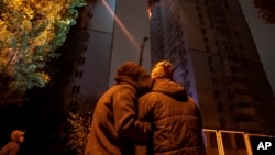 Una pareja se consuela mientras observa un incendio en un edificio residencial después de que drones rusos mataran a un adolescente en Kiev, Ucrania, el viernes 25 de octubre de 2024. AP