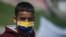 Un manifestante usa una máscara facial con los colores de la bandera colombiana durante una protesta que exige ayuda alimentaria del gobierno para los pobres, en medio del brote de la enfermedad del coronavirus.