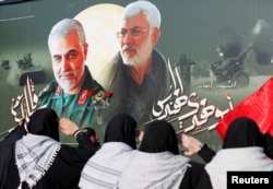 FILE - Iraqi women gather at the scene where Iran's Quds Force top commander Qassem Soleimani and Iraqi militia commander Abu Mahdi al-Muhandis were killed in a U.S. airstrike at Baghdad airport, Iraq, Feb. 13, 2020.