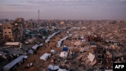 Palestinianos passam por tendas alinhadas nas ruas por entre os escombros de edifícios destruídos em Jabalia, no norte da Faixa de Gaza, a 18 de fevereiro de 2025