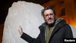 Olafur Eliasson, a Danish-Icelandic artist, poses in front of a block of ice that was havested in Greenland and transported in a refrigerated container for a project called "Ice Watch," in Paris, France, Dec. 3, 2015