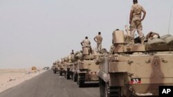 In this photo taken on Monday, Aug. 3, 2015, fighters against Shiite rebels known as Houthis stand on their armored vehicles on a road leading to Al-Anad base near Aden in the southern province of Lahej, Yemen.
