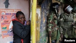 Une femme se cache et pleure à côté à des policiers lors des manifestations après la proclamation de la victoire du président Uhuru Kenyatta à la présidentielle à Nairobi, Kenya, 12 août 2017.