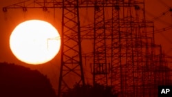 The sun rises next to power lines in Frankfurt, Germany, Tuesday, June 23, 2020. (AP Photo/Michael Probst)