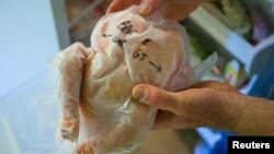 FILE - Jeff Nice holds a frozen chicken from his freezer at his farm in Kinston, North Carolina.