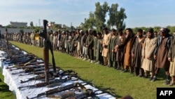 FILE - In this photograph taken on Nov. 17, 2019 members of the Islamic State (IS) group stand alongside their weapons, following they surrender to Afghanistan's government in Jalalabad, capital of Nangarhar Province. 