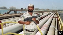 FILE - A security guard keeps watch over oil pipelines in Aramco refinery in Saudi Arabia.