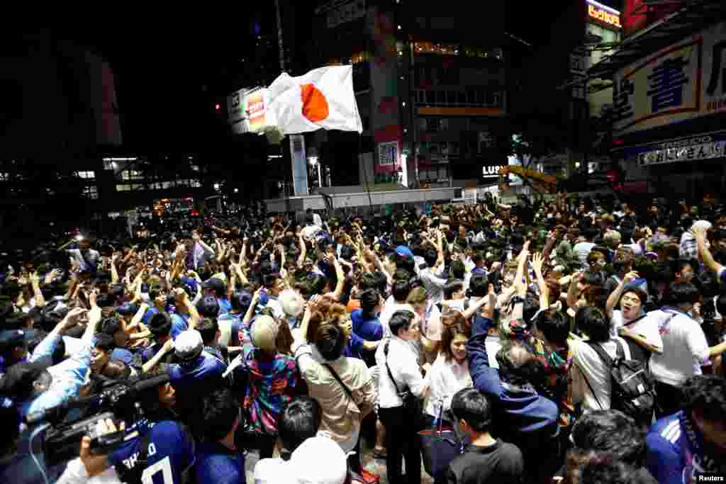 Soccer fans and pedestrians exchange high fives to praise Japan&#39;s soccer team players near a diagonal crosswalk after World Cup Group H soccer match Japan vs Senegal, at Shibuya district in Tokyo, Japan.