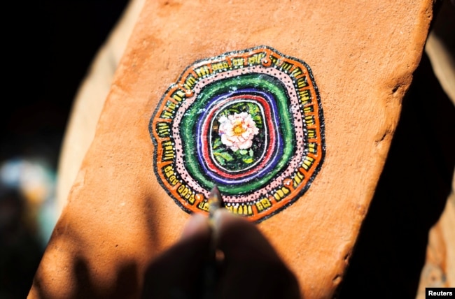 Ben Wilson, shows his painting on a piece of chewing gum, stuck on a brick, in his home studio in Muswell Hill, London, Britain, August 21, 2023. (REUTERS/Anna Gordon)