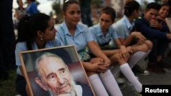 Des étudiants tiennent une image du feu président Fidel Castro attendant le passage de la caravane accompagnant la cendre de celui-ci à Camaguey, Cuba, 1er décembre 2016. 