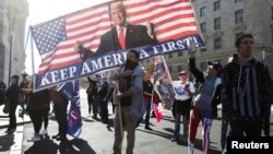 Seorang pendukung Presiden AS Donald Trump membawa spanduk dalam demo "Stop the Steal" di Washington D.C, untuk memprotes hasil pilpres AS yang diproyeksikan dimenangkan oleh capres Partai Demokrat, Joe Biden, Sabtu, 14 November 2020. (Foto: Reuters)