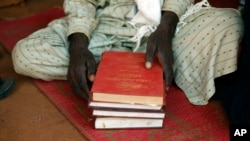 FILE - A Muslim man holds copies of the Koran at the central mosque in Yaloke, north of Bangui, Central African Republic.