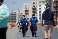 Police officers patrol the boardwalk at Long Beach on the first day that New York beaches were opened ahead of the Memorial Day weekend following the outbreak of the coronavirus pandemic, on Long Island, New York, May 22, 2020.