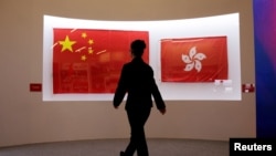 Bendera China (Kiri) dan Hong Kong yang digunakan selama upacara penyerahan Hong Kong 1997 dipajang selama pameran untuk merayakan ulang tahun ke-20 penyerahannya ke pemerintahan China, di Museum Nasional China di Beijing 27 Juni 2017. (Foto: Reuters)