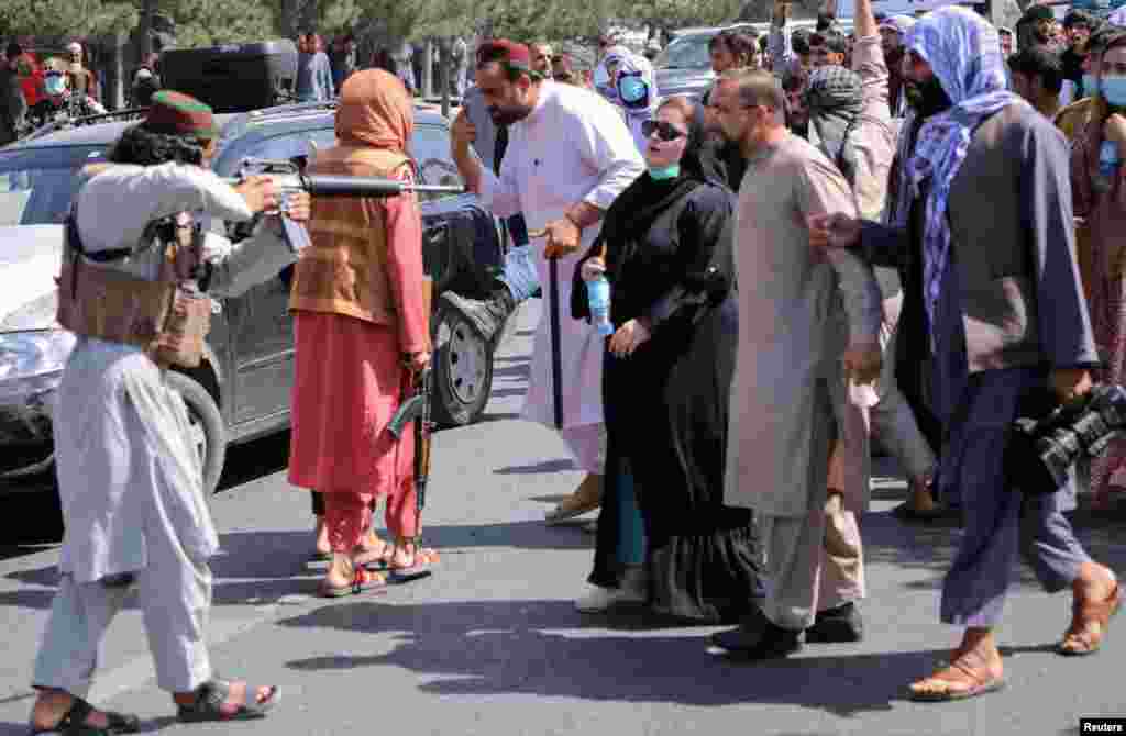 A member of the Taliban forces points his gun at protesters, as Afghan demonstrators shout slogans during an anti-Pakistan protest, near the Pakistan embassy in Kabul, Afghanistan.