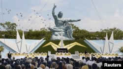 Burung merpati terbang melewati Patung Perdamaian di Taman Perdamaian Nagasaki dalam upacara peringatan 70 tahun pemboman kota tersebut, di Nagasaki, Jepang barat. Foto oleh Kyodo, 9 Agustus 2015. 