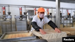 FILE - A worker wearing a face mask works on a production line manufacturing soybean-based food products at a factory in Hefei, Anhui province, China, Feb. 4, 2020. 