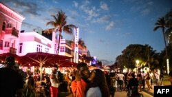 People gather on Ocean Drive in Miami Beach, on March 22, 2021. The city of Miami Beach, overrun by crowds of spring break tourists, has extended a state of emergency to stem the chaos.