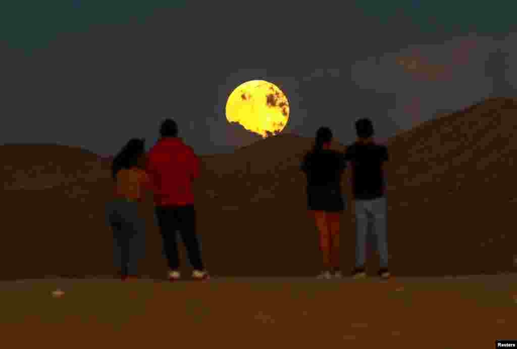 Personas observan la salida de la luna llena antes del eclipse lunar en las Dunas de Samalayuca, en las afueras de Ciudad Juárez, México, el 17 de septiembre de 2024.&nbsp;