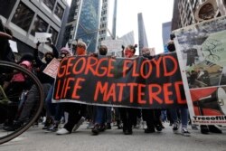 People hold signs as they march during a protest over the death of George Floyd, in Chicago, Illinois, May 30, 2020.