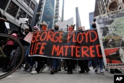 People hold signs as they march during a protest over the death of George Floyd, in Chicago, Illinois, May 30, 2020.