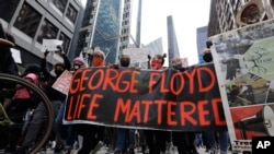 People hold signs as they march during a protest over the death of George Floyd, in Chicago, Illinois, May 30, 2020. 